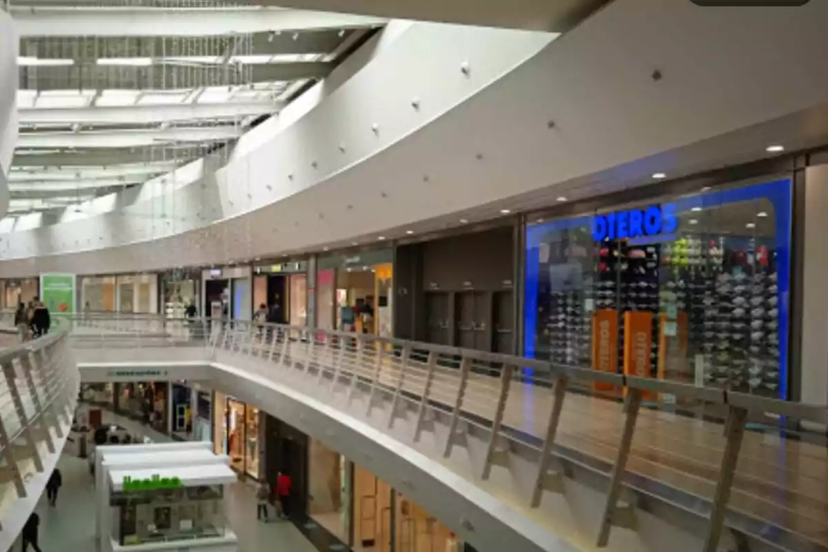 Interior de un centro comercial moderno con varias tiendas y un diseño arquitectónico curvo. Interior de un centro comercial moderno con varias tiendas y un diseño arquitectónico curvo.