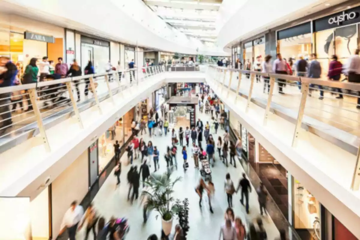 Personas caminando en un centro comercial concurrido con tiendas a los lados. Personas caminando en un centro comercial concurrido con tiendas a los lados.