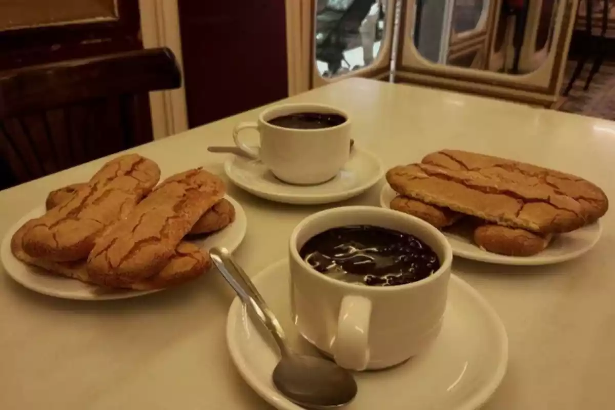 Dos vasos de chocolate caliente con dos platos con melindros Dos vasos de chocolate caliente con dos platos con melindros