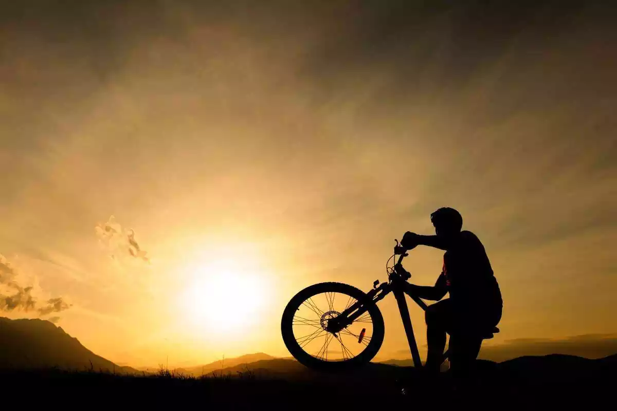 Ciclista yendo en bicicleta por la montaña en pleno amanecer