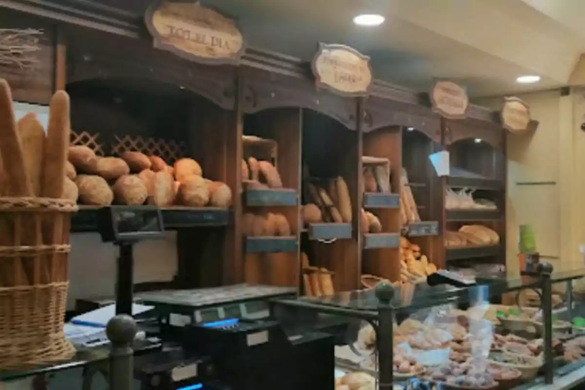 Una panadería con estantes llenos de diferentes tipos de panes y bollería detrás de un mostrador de vidrio. Una panadería con estantes llenos de diferentes tipos de panes y bollería detrás de un mostrador de vidrio.