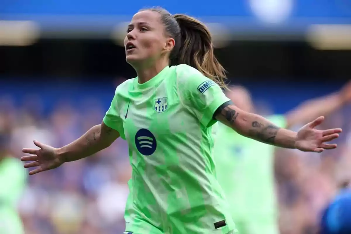 Futbolista con uniforme verde celebrando un gol con los brazos extendidos en un estadio Futbolista con uniforme verde celebrando un gol con los brazos extendidos en un estadio