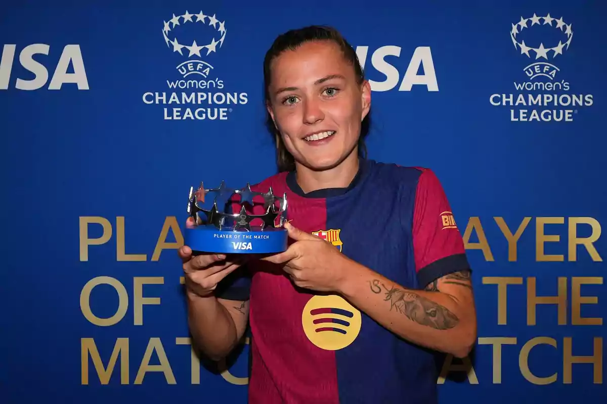 Una jugadora de fútbol sonríe mientras sostiene un trofeo de Una jugadora de fútbol sonríe mientras sostiene un trofeo de