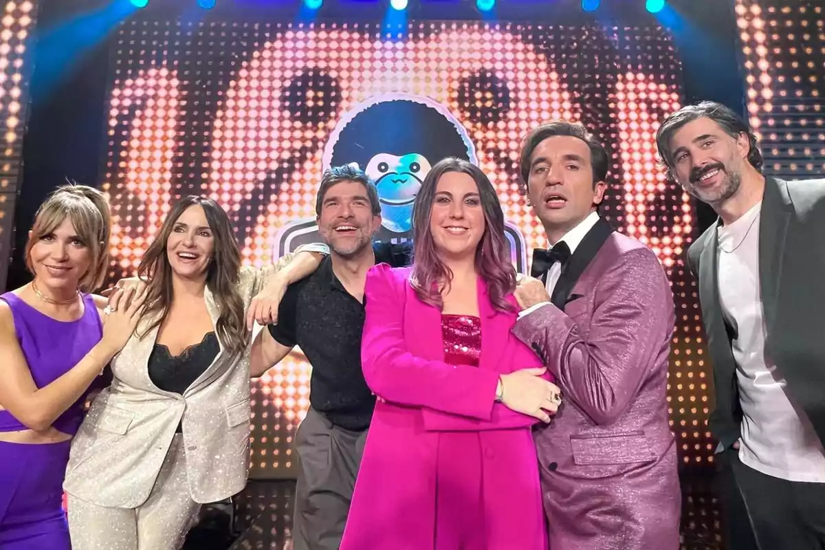 María Gómez, Melani Olivares, Nacho García, Carolina Iglesias, Miguel Lago y David Amor posando juntas en un escenario con un fondo iluminado y colorido en El Club del Chiste.