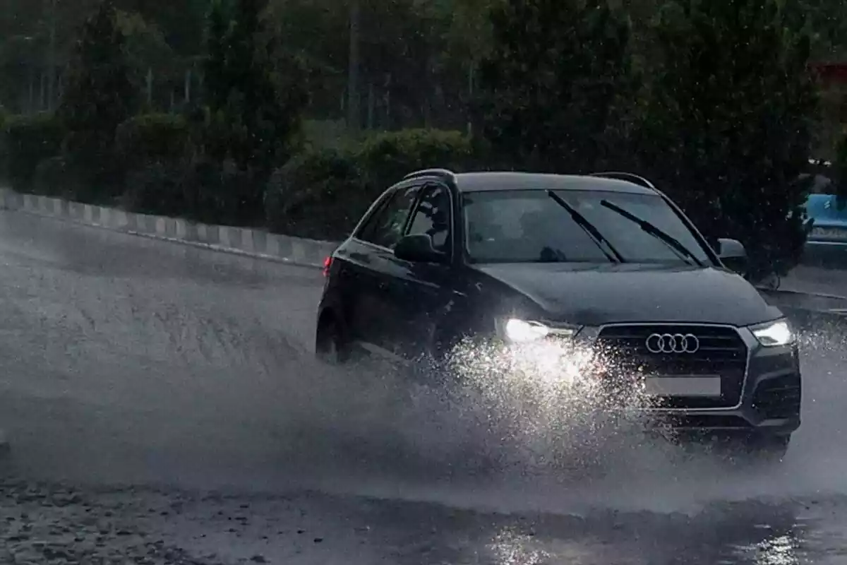 Un coche atravesando un charco de agua en medio de una tormenta