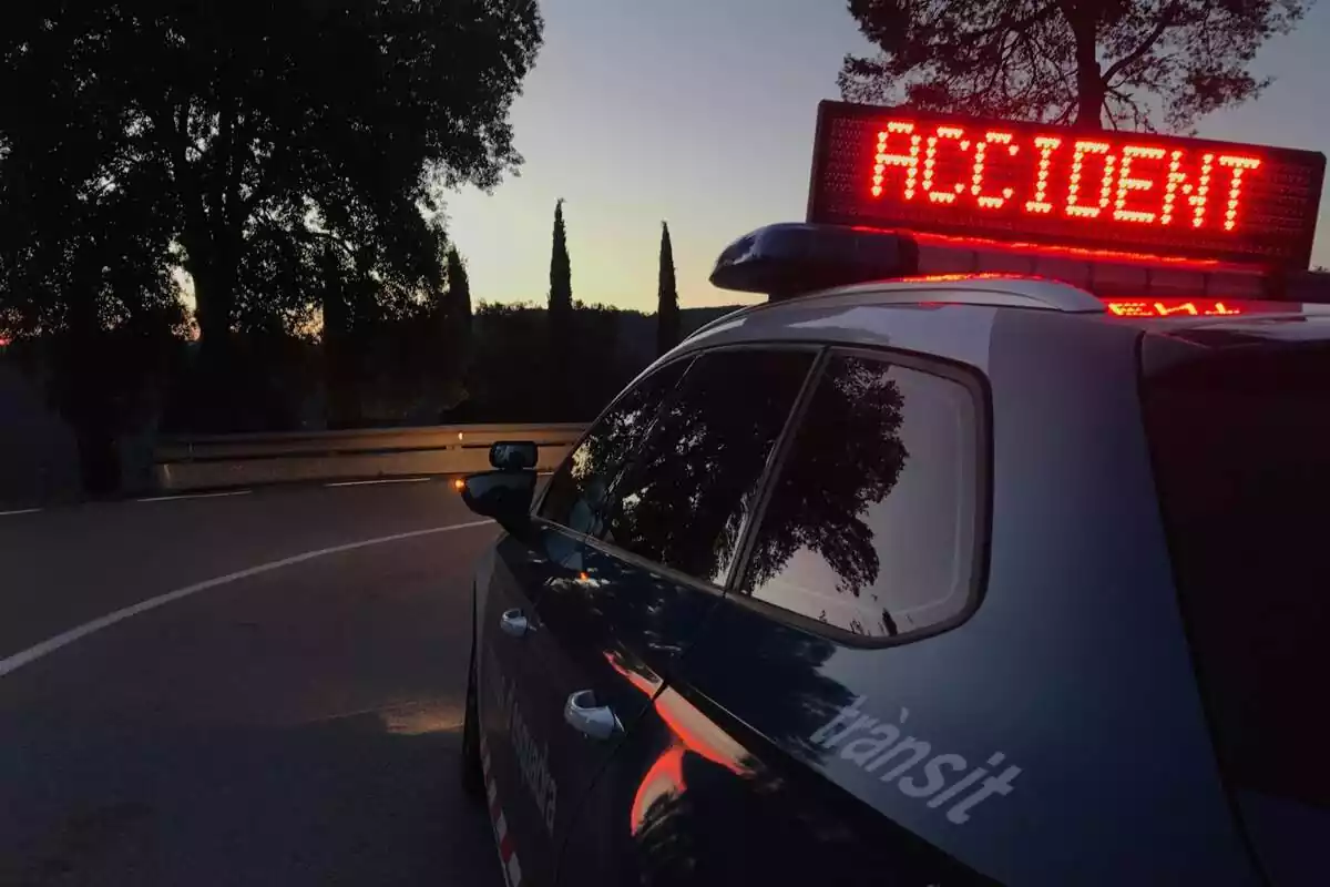 Plano corto de un coche de los Mossos d'Esquadra que tiene el cartel de 'Accidente' enmedio de una carretera