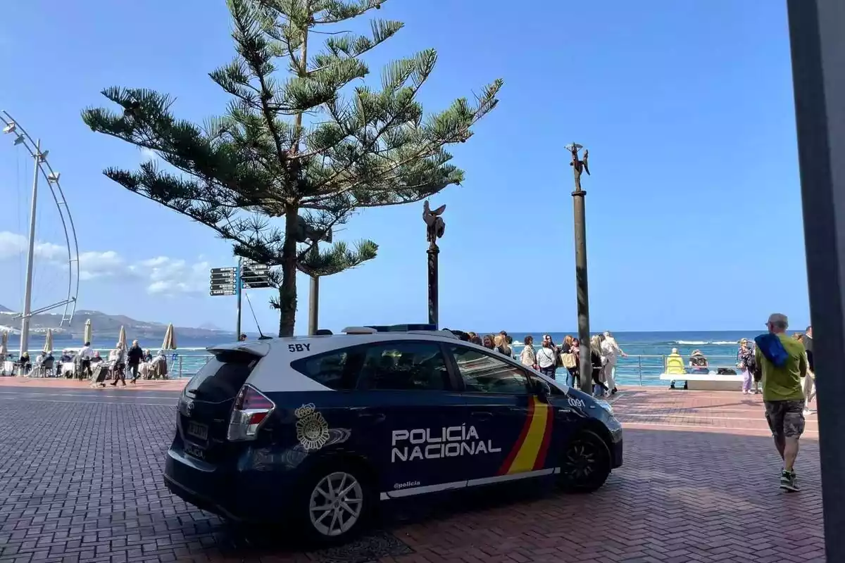 Un coche de policía nacional aparcado al lado de un paseo marítimo