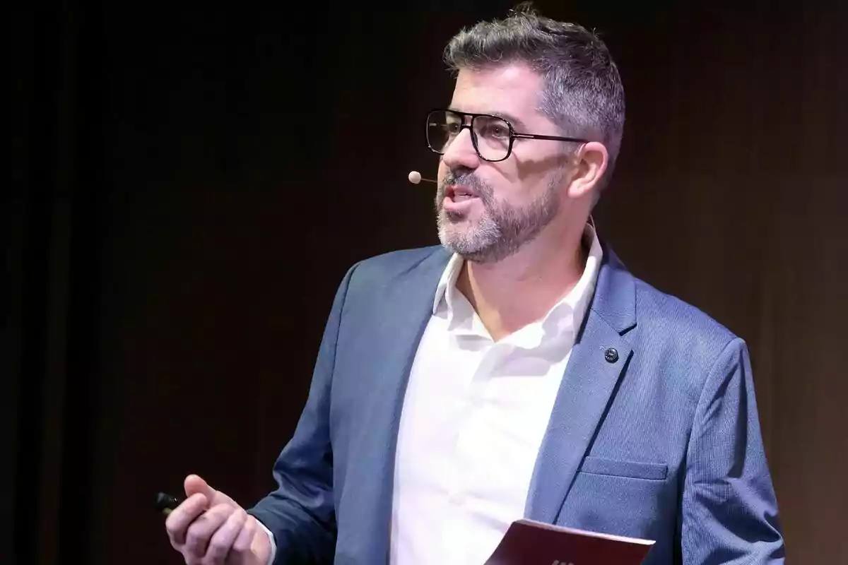 Cristian Trepat con gafas y barba usando micrófono de diadema mientras da una presentación de 3Cat Cristian Trepat con gafas y barba usando micrófono de diadema mientras da una presentación de 3Cat