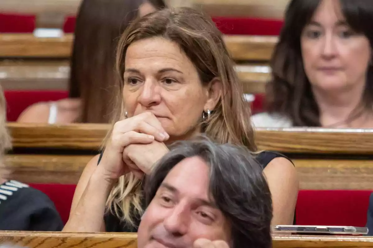 Cristina Casol, sentada en su escaño en el Parlament de Catalunya, con los codos apoyados en la mesa y sus puños, juntos, entre la barbilla y la boca