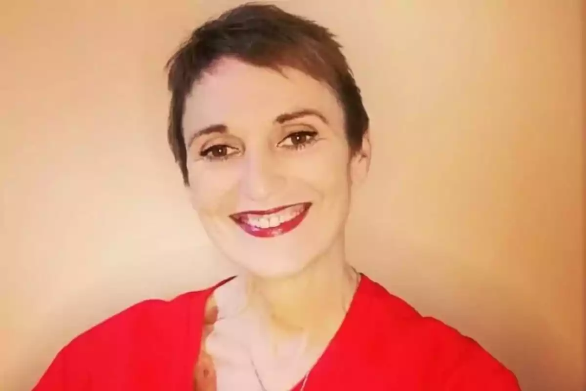 Cristina Fenollar de cabello corto y oscuro sonríe a la cámara, lleva puesta una camiseta roja y está frente a un fondo beige. Cristina Fenollar de cabello corto y oscuro sonríe a la cámara, lleva puesta una camiseta roja y está frente a un fondo beige.
