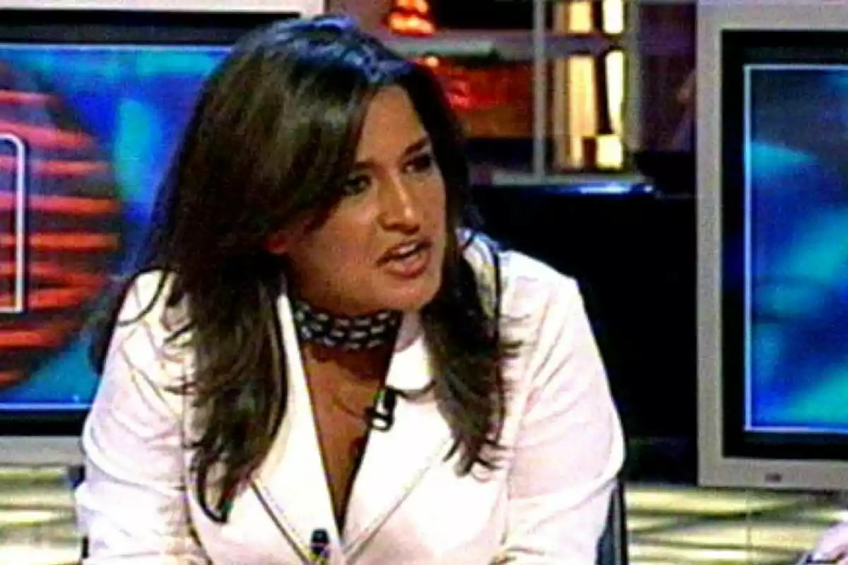 Aída Nízar con chaqueta blanca y cabello oscuro hablando en un programa de televisión con pantallas de fondo. Aída Nízar con chaqueta blanca y cabello oscuro hablando en un programa de televisión con pantallas de fondo.