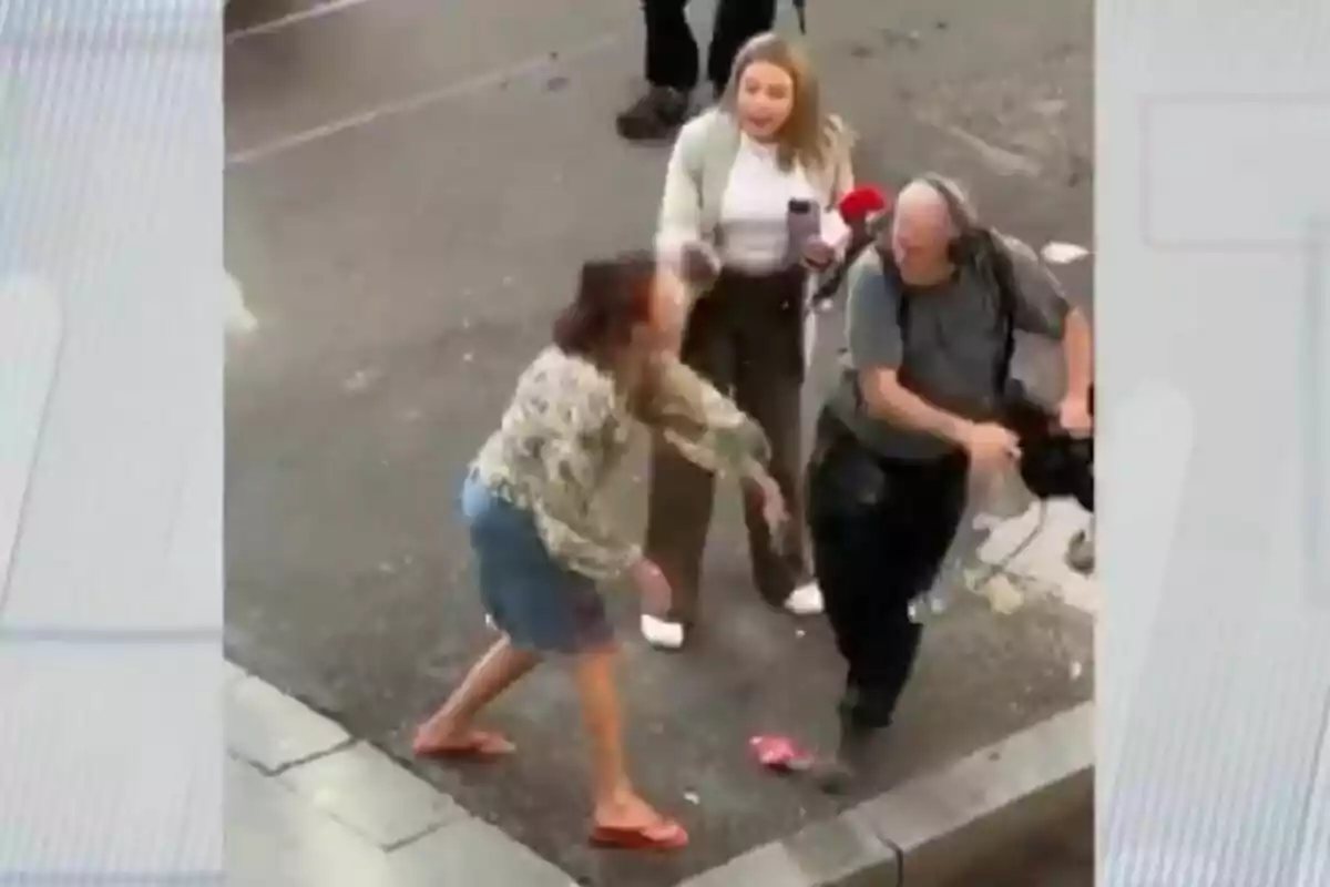 Una mujer parece estar agrediendo a un camarógrafo mientras otra persona observa la escena en una calle.