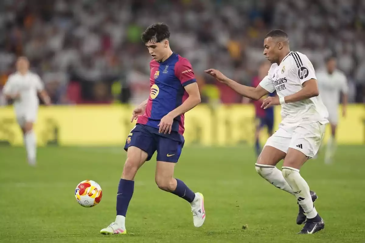 Dos jugadores de fútbol en acción durante un partido, uno con uniforme azul y rojo y el otro con uniforme blanco, mientras el balón está en el aire. Dos jugadores de fútbol en acción durante un partido, uno con uniforme azul y rojo y el otro con uniforme blanco, mientras el balón está en el aire.