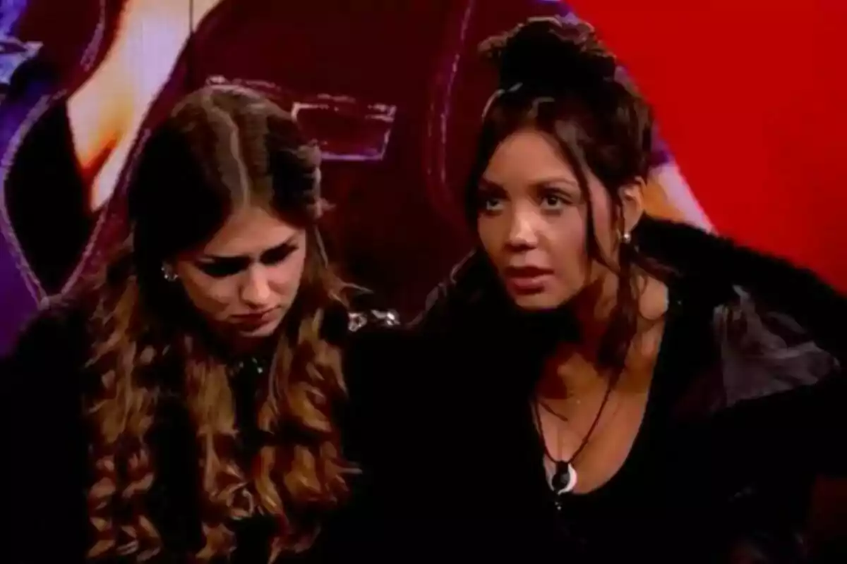 Maica y Daniela sentadas en la sala de expulsión de Gran Hermano con un ambiente con fondo rojo, una de ellas parece preocupada mientras la otra la observa atentamente.