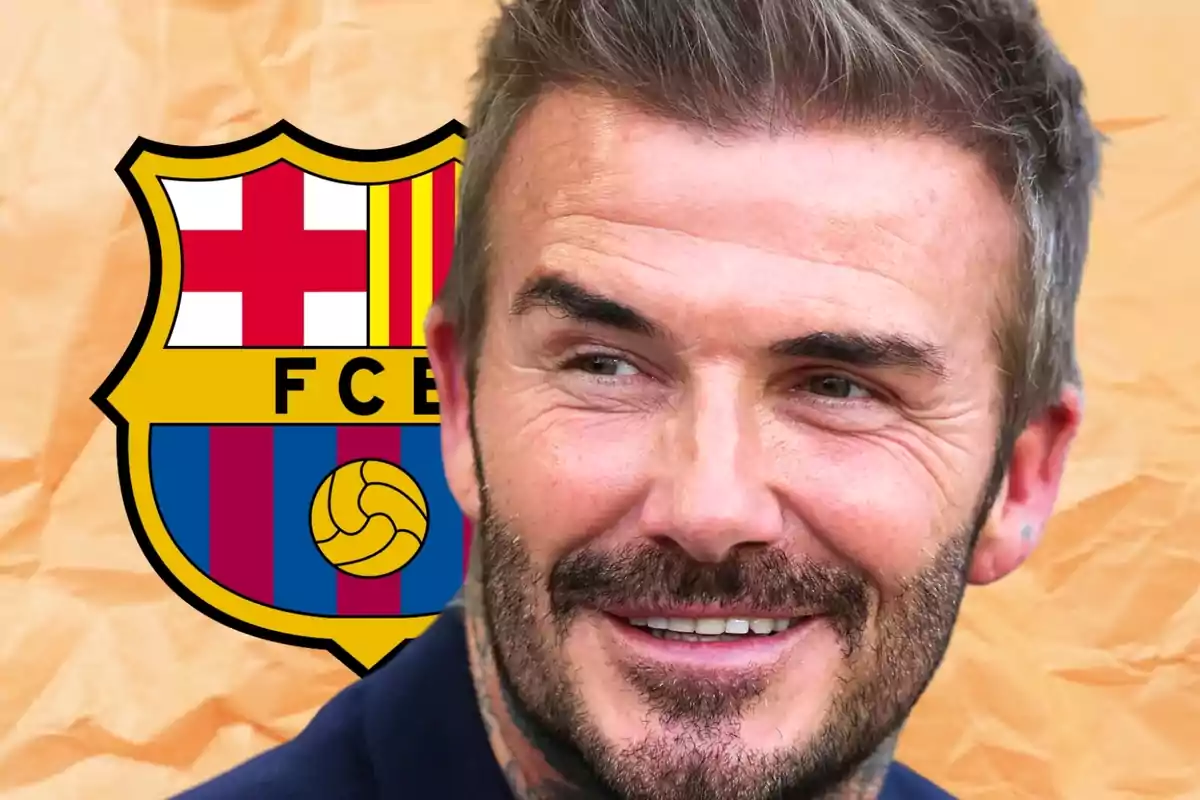 Un hombre sonriente con barba y cabello corto frente al escudo del FC Barcelona.