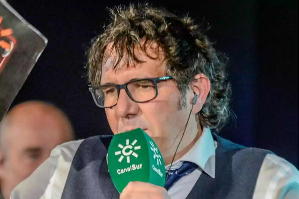 David Gallardo con gafas y auriculares sostiene un micrófono verde de Canal Sur.