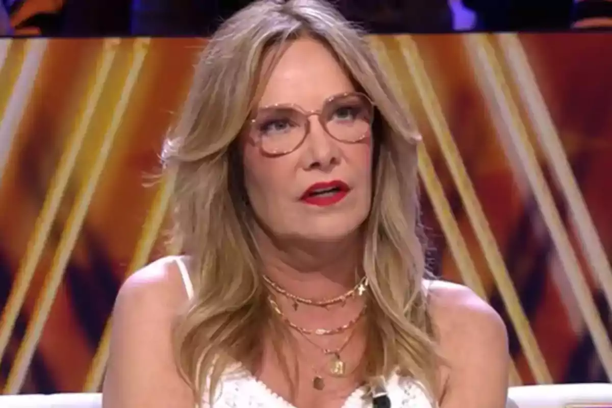 Belén Rodríguez está sentada en un plató de televisión con un fondo de colores cálidos.