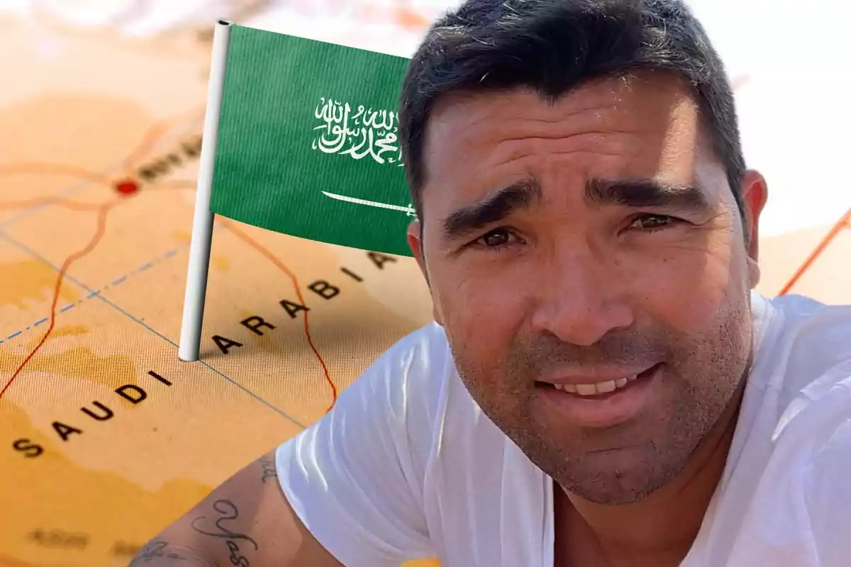 Hombre con camiseta blanca sonriendo frente a un mapa de Arabia Saudita con una bandera saudí.