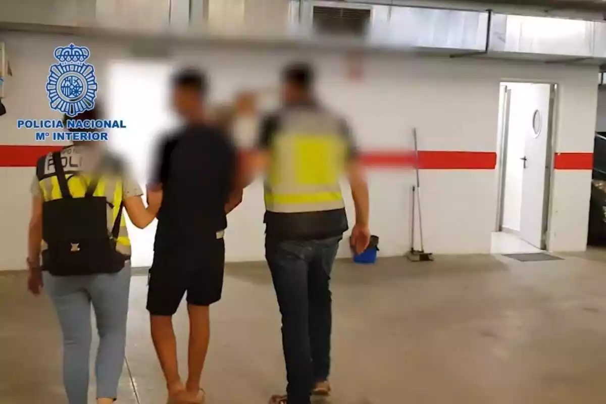 Dos policías nacionales deteniendo a un joven acusado de participar en una red de violencia de género en el interior de un parking