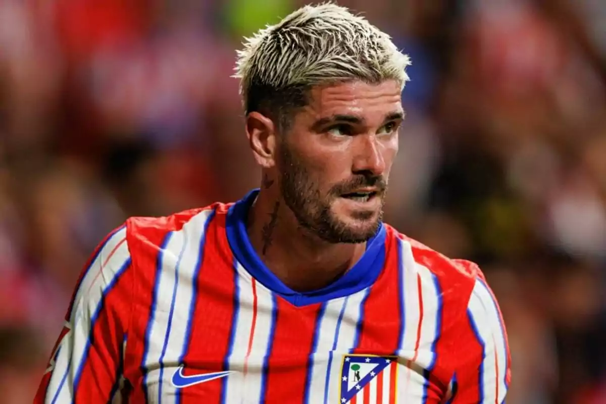 Un jugador de fútbol con cabello rubio y barba viste una camiseta a rayas rojas y blancas con detalles azules. Un jugador de fútbol con cabello rubio y barba viste una camiseta a rayas rojas y blancas con detalles azules.