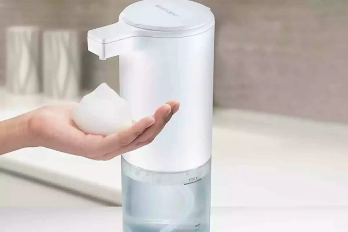 Una mano recibiendo espuma de un dispensador automático de jabón. Una mano recibiendo espuma de un dispensador automático de jabón.