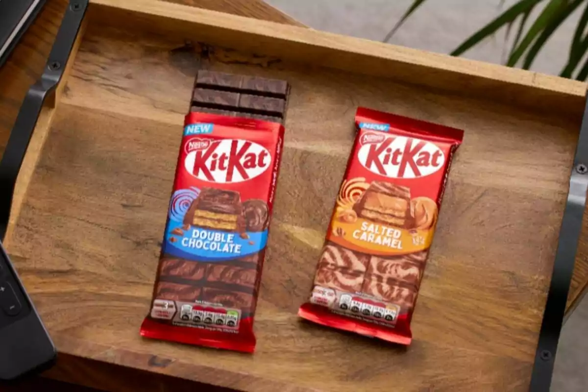 Dos barras de chocolate KitKat sobre una bandeja de madera, una de doble chocolate y otra de caramelo salado. Dos barras de chocolate KitKat sobre una bandeja de madera, una de doble chocolate y otra de caramelo salado.