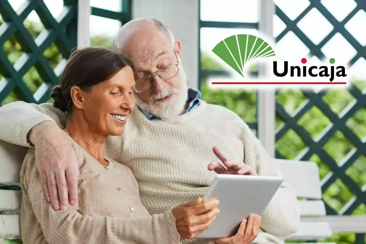 Pareja de personas mayores sonriendo mientras usan una tableta, con el logotipo de Unicaja en la esquina superior derecha.