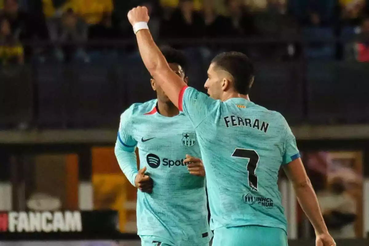 Dos jugadores del Barça en el campo de futbol, uno de ellos con el puño hacia arriba