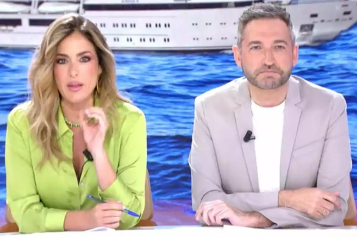 Verónica Dulanto y Frank Blanco están sentados en 'Tardear' con fondo de mar y un barco, la mujer lleva una camisa verde y el hombre un saco claro