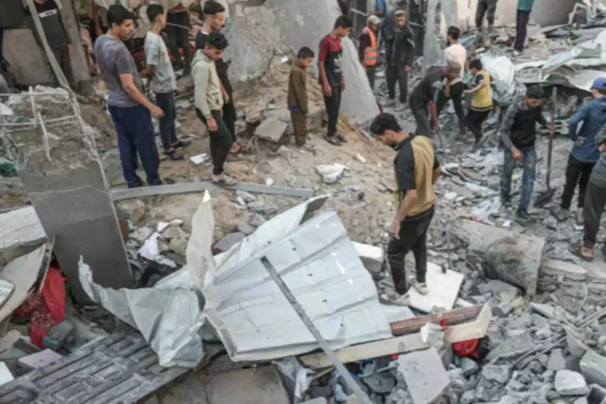 Varias personas observan y caminan entre los escombros de un edificio destruido Varias personas observan y caminan entre los escombros de un edificio destruido