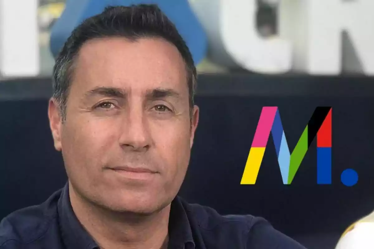 Eduardo Blanco de cabello corto y oscuro con camisa azul, al fondo un logotipo colorido de Mediaset con la letra M y un punto azul