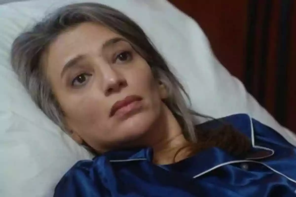 Efsun de cabello canoso acostada en una cama con pijama azul en Renacer. Efsun de cabello canoso acostada en una cama con pijama azul en Renacer.