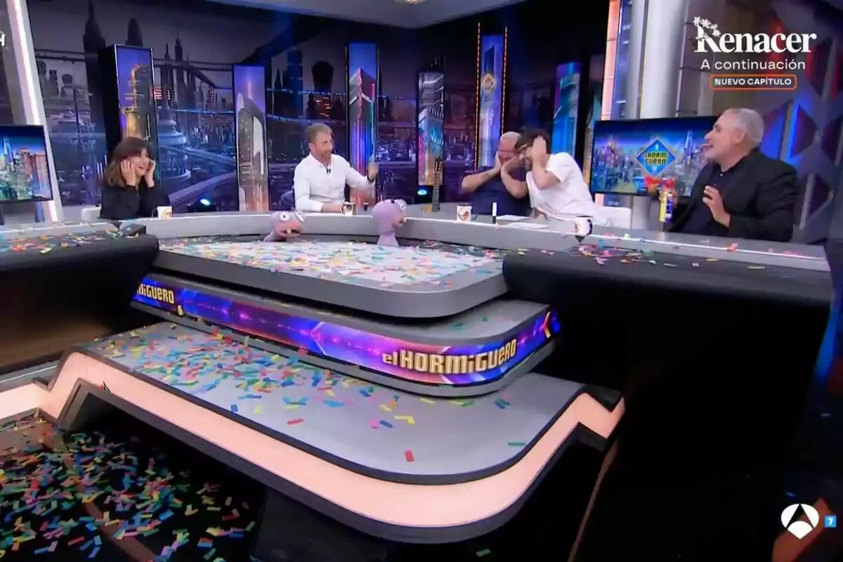 Personas sentadas alrededor de una mesa de 'El Hormiguero' cubierto de confeti, con marionetas y ambiente festivo Personas sentadas alrededor de una mesa de 'El Hormiguero' cubierto de confeti, con marionetas y ambiente festivo