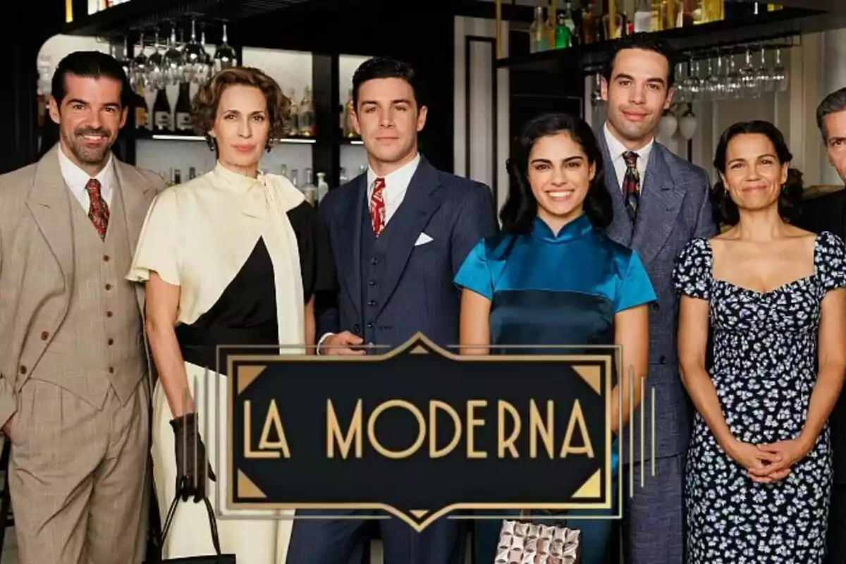 Un grupo de personas formado por Miguel Ángel Muñoz, Jesús Mosquera, Pepe Nufrio o Lola Marceli, elegantemente vestidas posando frente a un bar con el logo de "La Moderna" en primer plano.