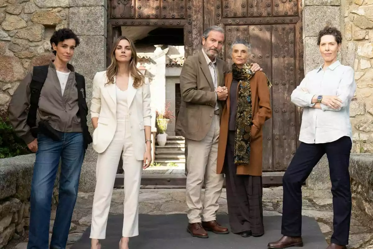 Ángela Molina, Pep Munné, Amaia Salamanca, Aitor Luna y Blanca Romero posan frente a una puerta de madera antigua, dos de ellas están abrazadas, mientras que las otras tres están de pie con expresiones serias en el rodaje de Pura Sangre.