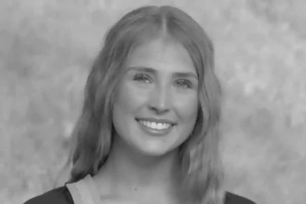 Fotografía en blanco y negro de Emily Gold joven sonriendo frente a un fondo desenfocado.