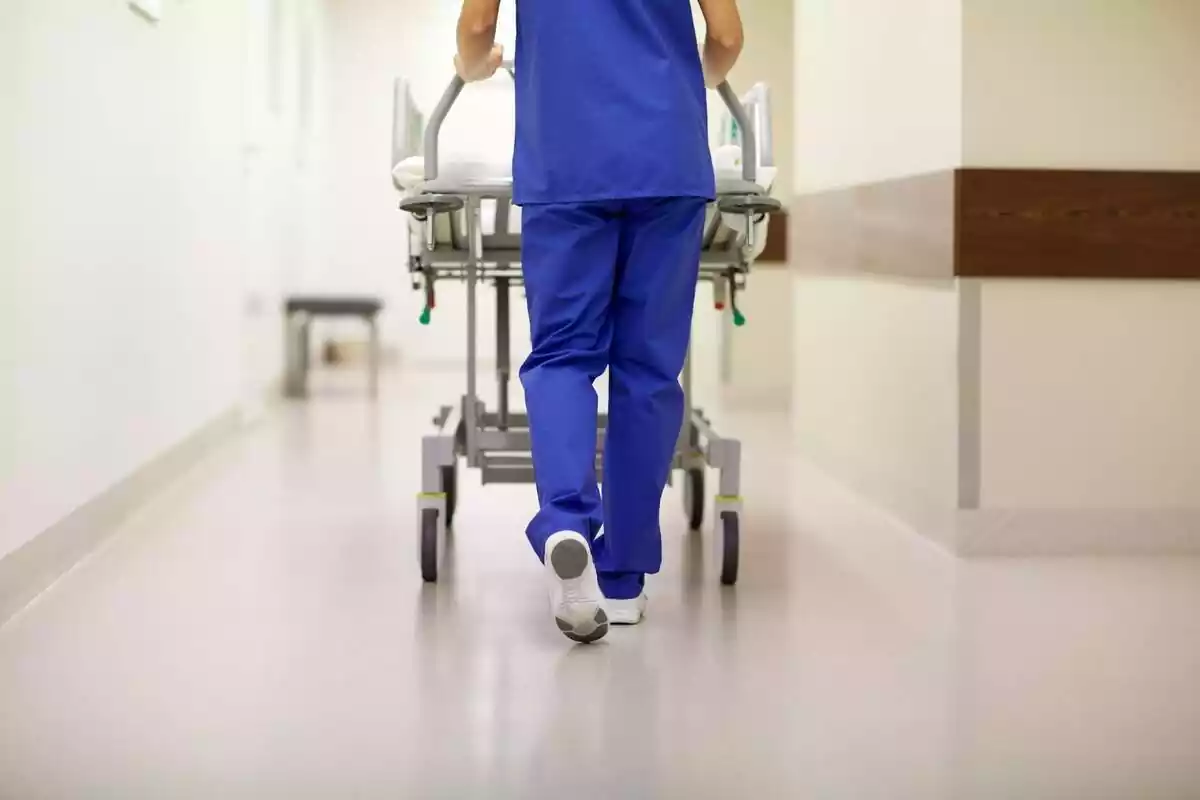 Imagen de espaldas del medio cuerpo inferior de una enfermera empujando una camilla