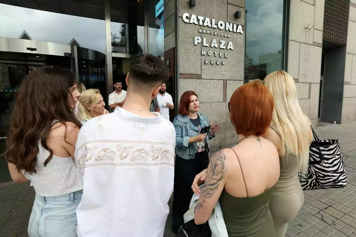 Un grupo de personas está reunido frente a la entrada del Catalonia Barcelona Plaza Hotel, mientras una mujer les habla con Teresa Colomina, directora de casting de Gran Hermano