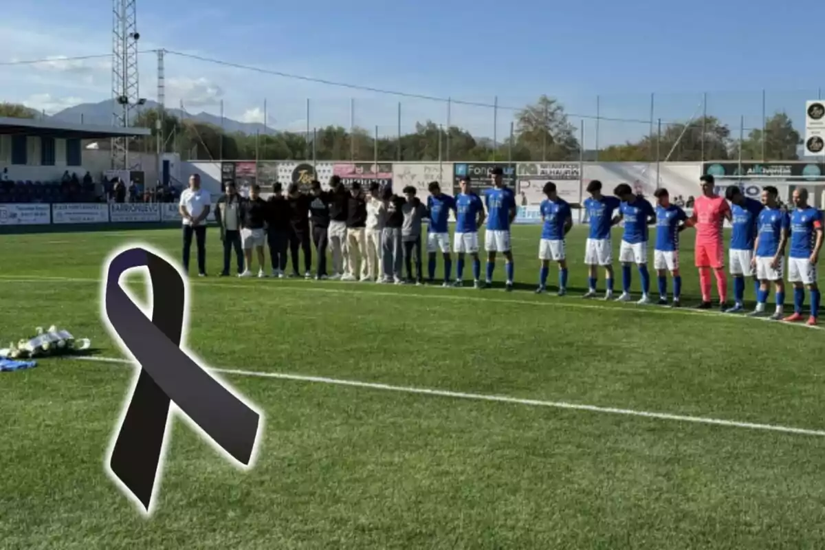 Un equipo de fútbol y otras personas guardan un minuto de silencio en el campo, con un lazo negro en señal de luto.