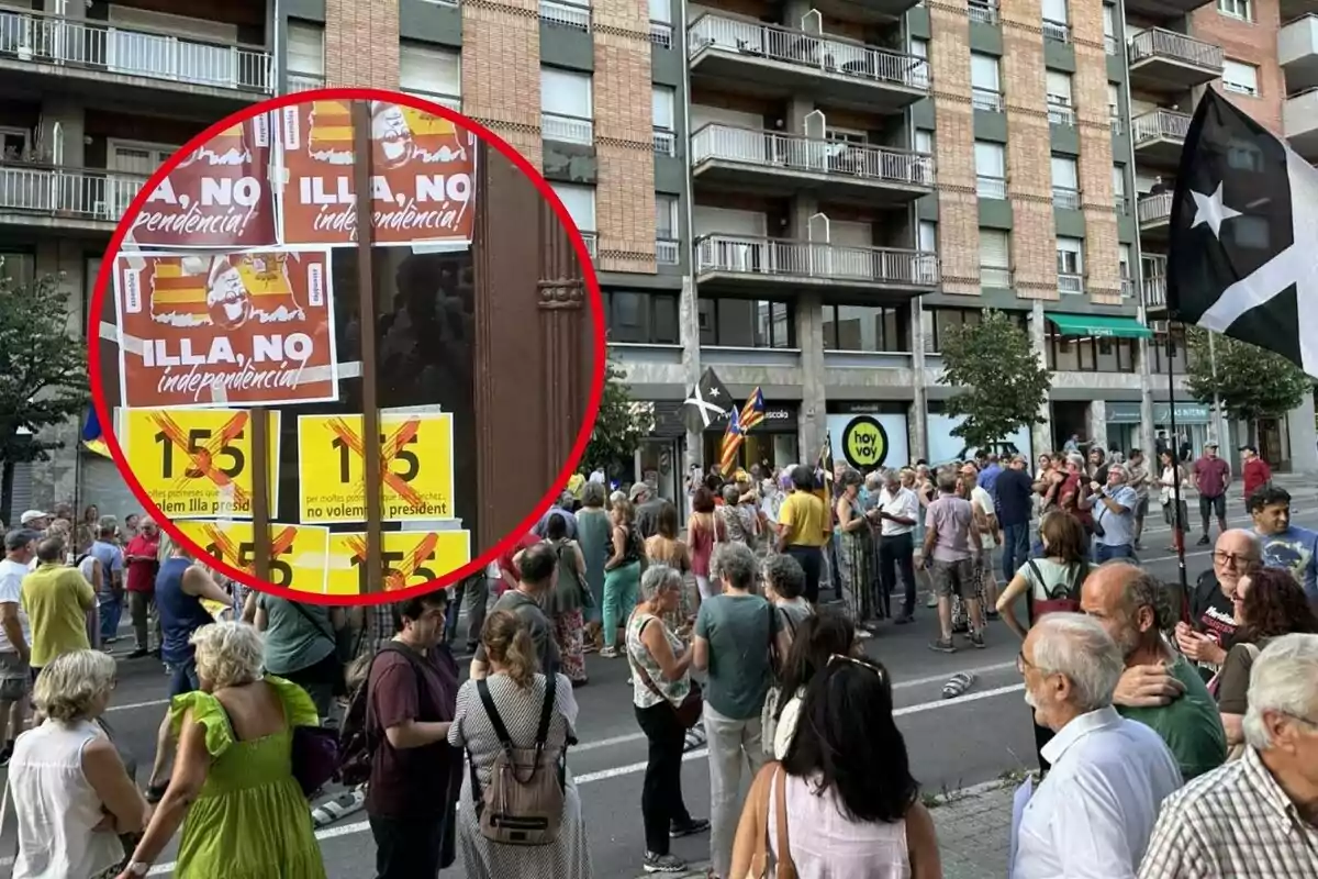 Una multitud de personas se ha reunido en una calle, con carteles y banderas que expresan mensajes políticos, destacando uno que dice "ILLA, NO independencia" y otros que rechazan el artículo 155.