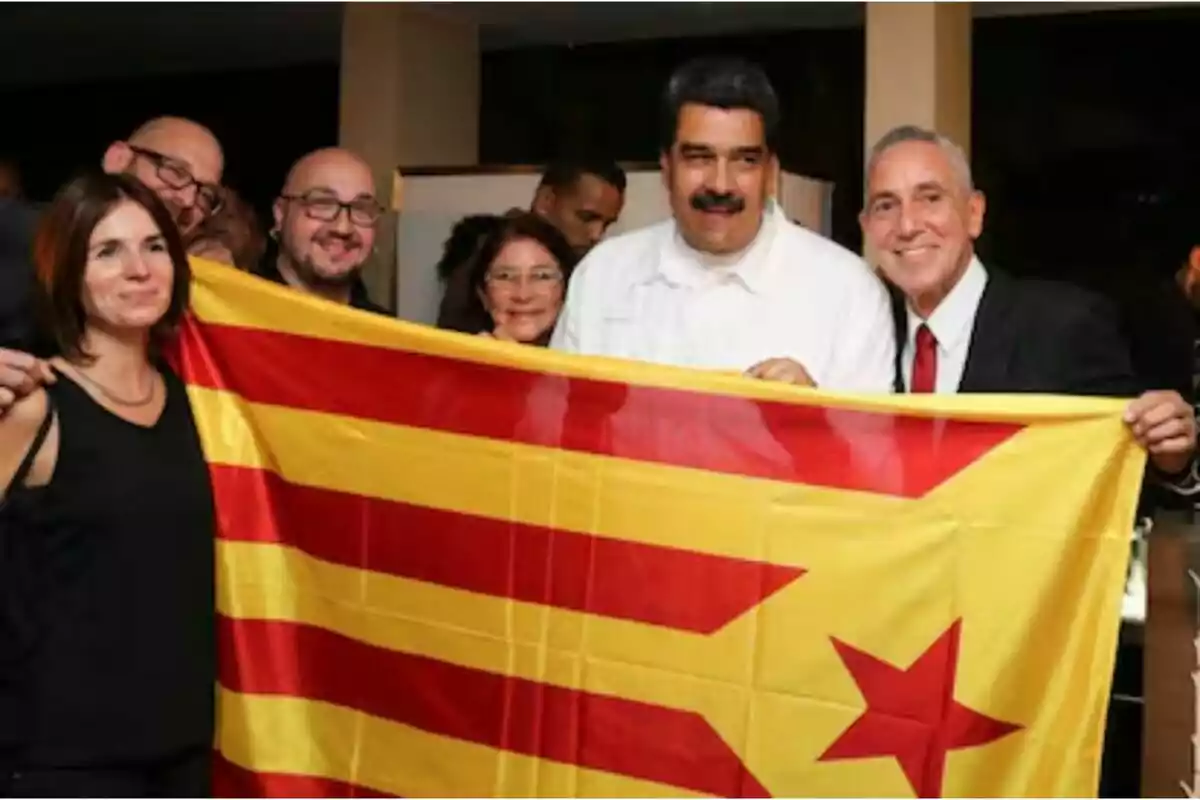 Un grupo de personas sosteniendo una bandera con franjas rojas y amarillas y una estrella roja.