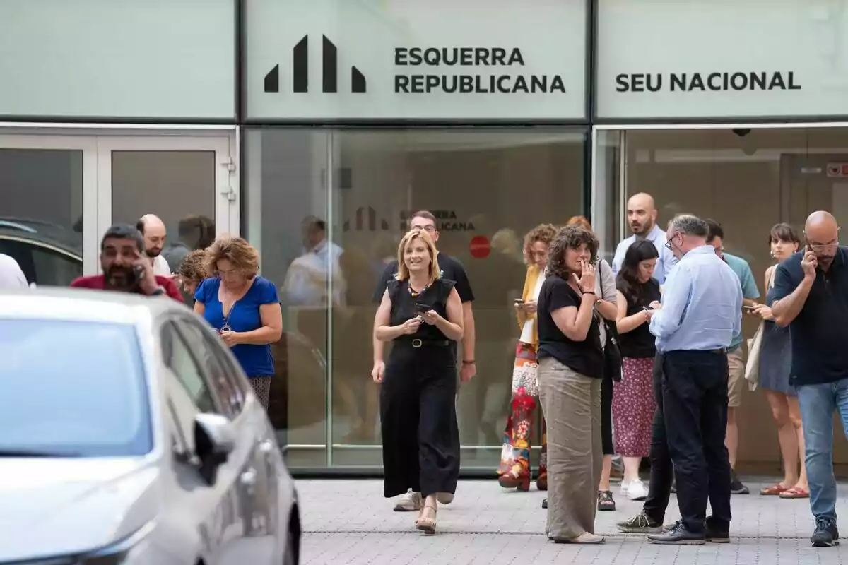 Varias personas están reunidas frente a un edificio con el letrero "Esquerra Republicana Seu Nacional". En primer plano, Raquel Sans