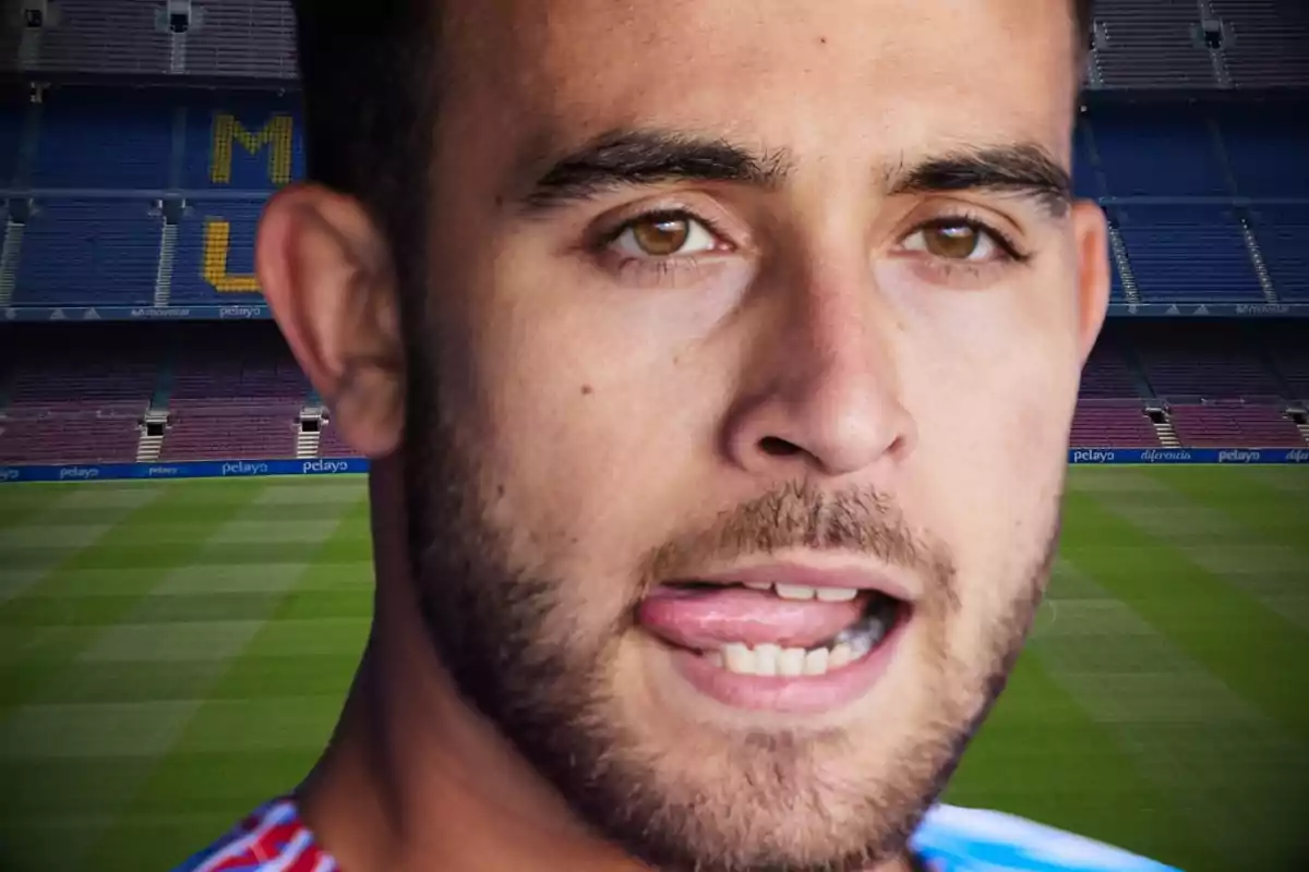 Un hombre con barba y cabello corto, con la lengua ligeramente fuera, en un estadio de fútbol vacío.