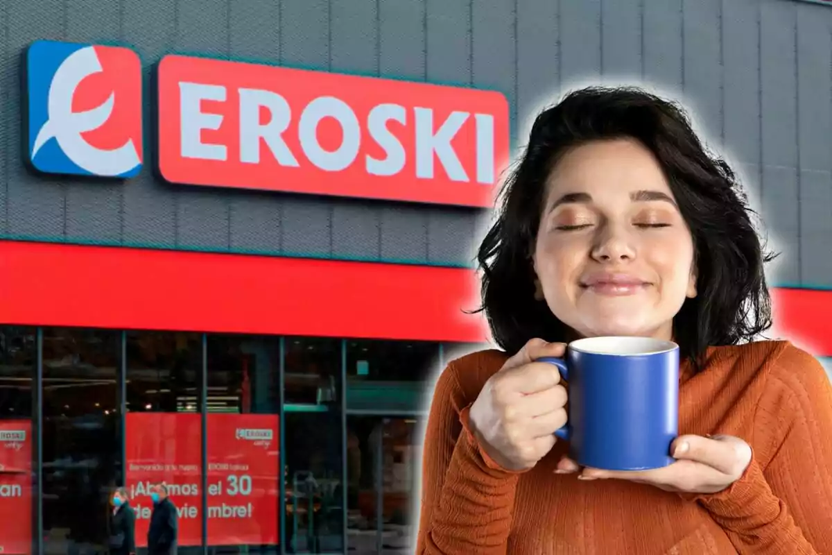 Una mujer sosteniendo una taza azul frente a una tienda Eroski.