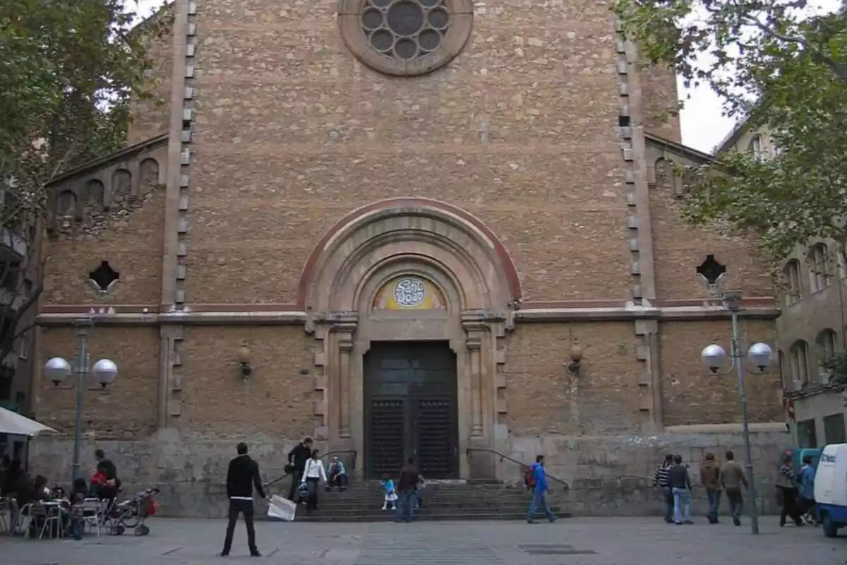 Fachada de la iglesia de San Juan Bautista de Gracia, Barcelona, con varias personas andando delante de ella