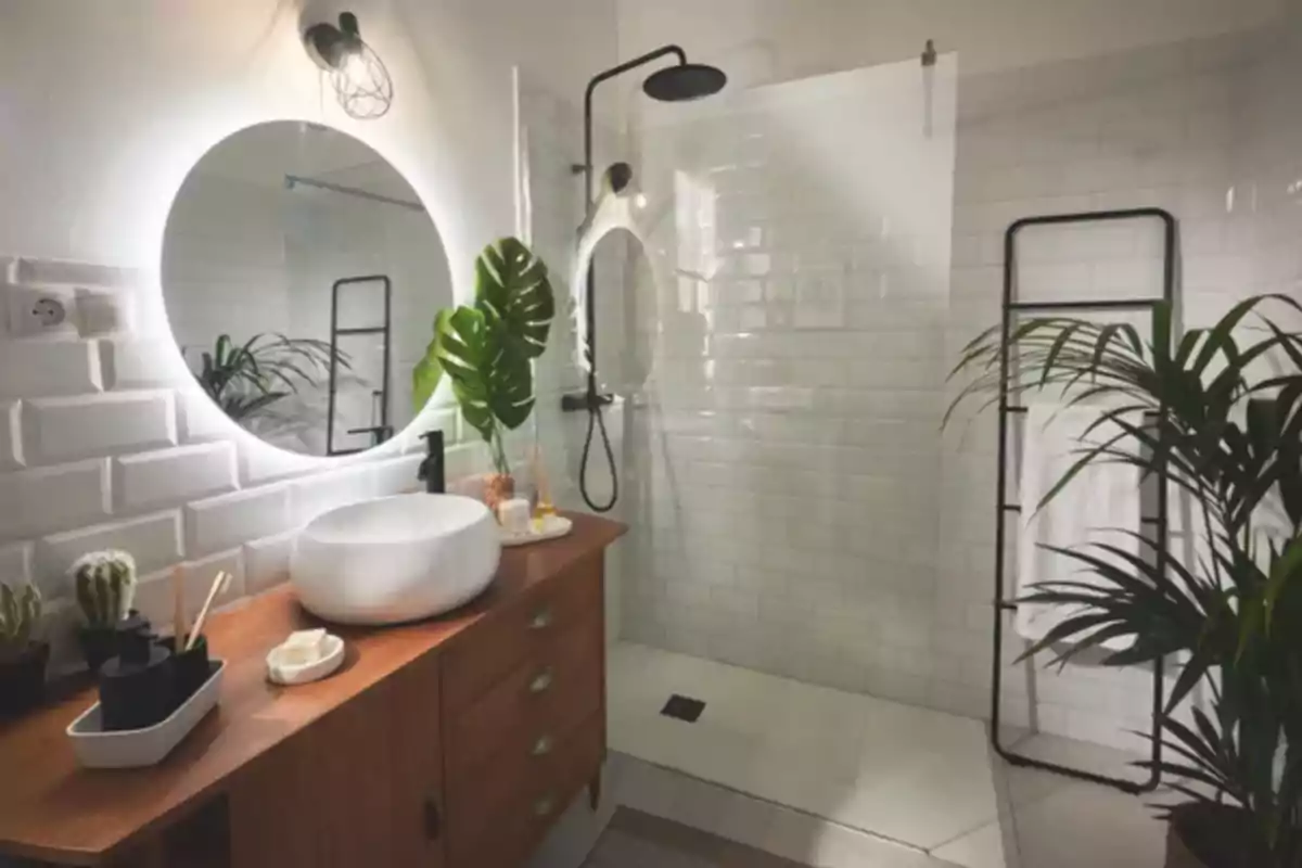Un baño moderno con azulejos blancos, un espejo redondo iluminado, un lavabo sobre una encimera de madera y plantas decorativas. Un baño moderno con azulejos blancos, un espejo redondo iluminado, un lavabo sobre una encimera de madera y plantas decorativas.