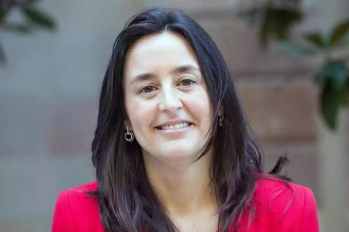 Mujer de cabello oscuro y lacio con chaqueta roja sonriendo frente a un fondo desenfocado Mujer de cabello oscuro y lacio con chaqueta roja sonriendo frente a un fondo desenfocado