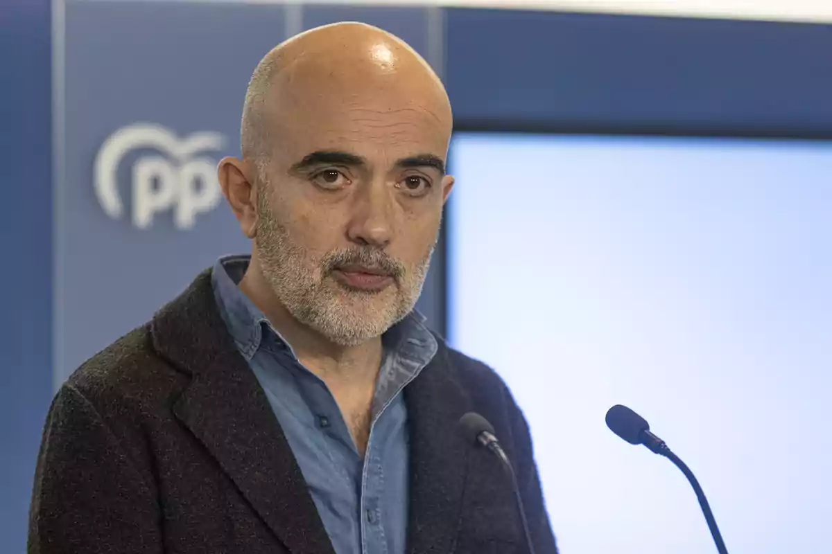 Daniel Sirera a hablando en una conferencia de prensa con un fondo azul y el logotipo del PP.