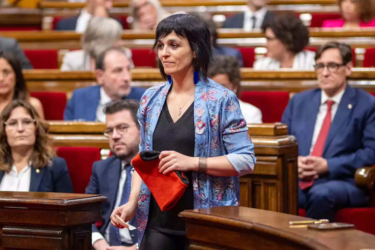 Una mujer de pie en una sala de reuniones con varias personas sentadas en el fondo.