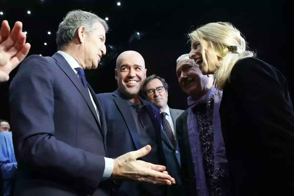 Un grupo de personas conversando y sonriendo en un evento formal. Un grupo de personas conversando y sonriendo en un evento formal.